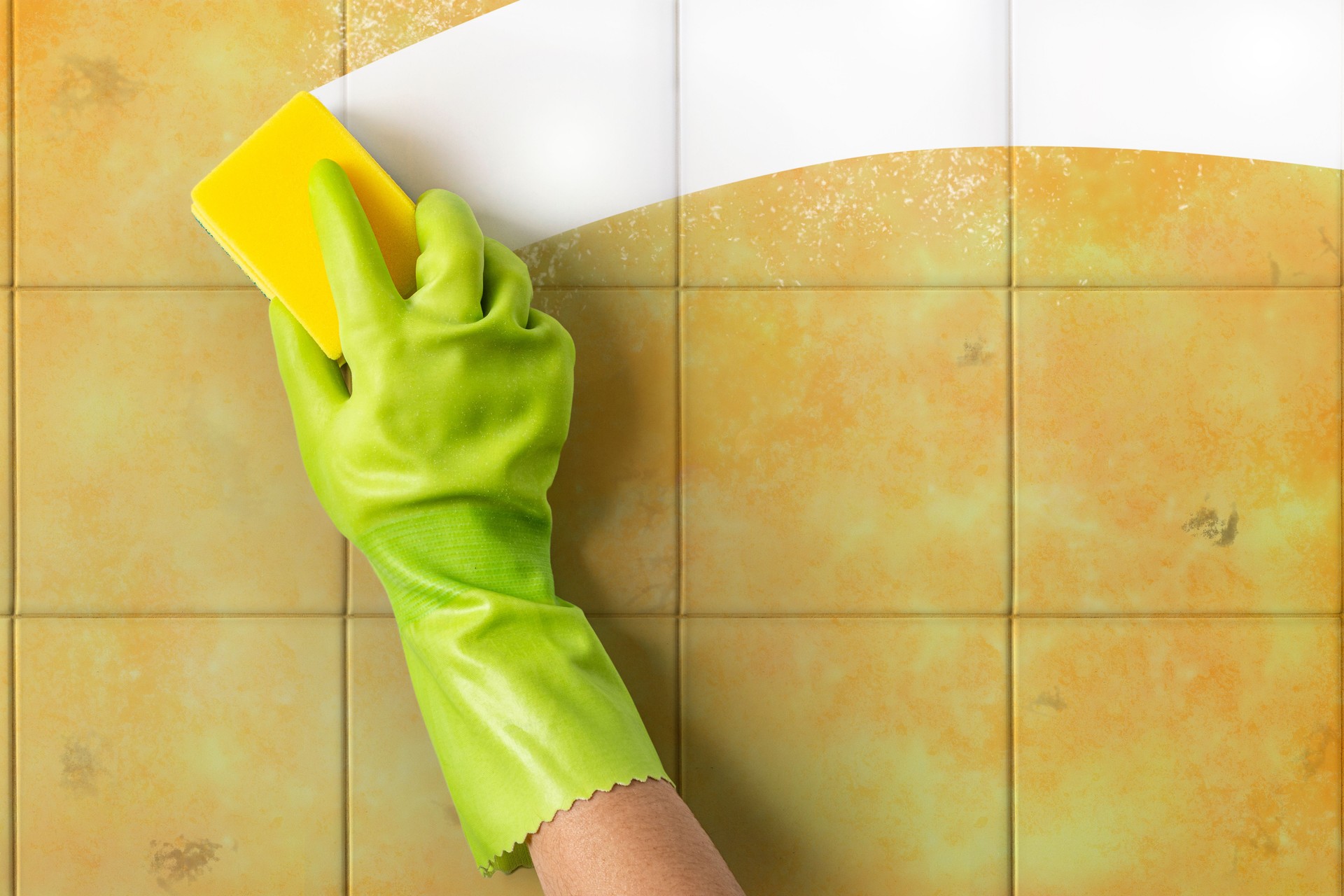 Hand cleaning a dirty ceramic tile wall with a sponge